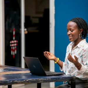 Smiling African woman with dreadlocks having an online video call in a colorful office.
